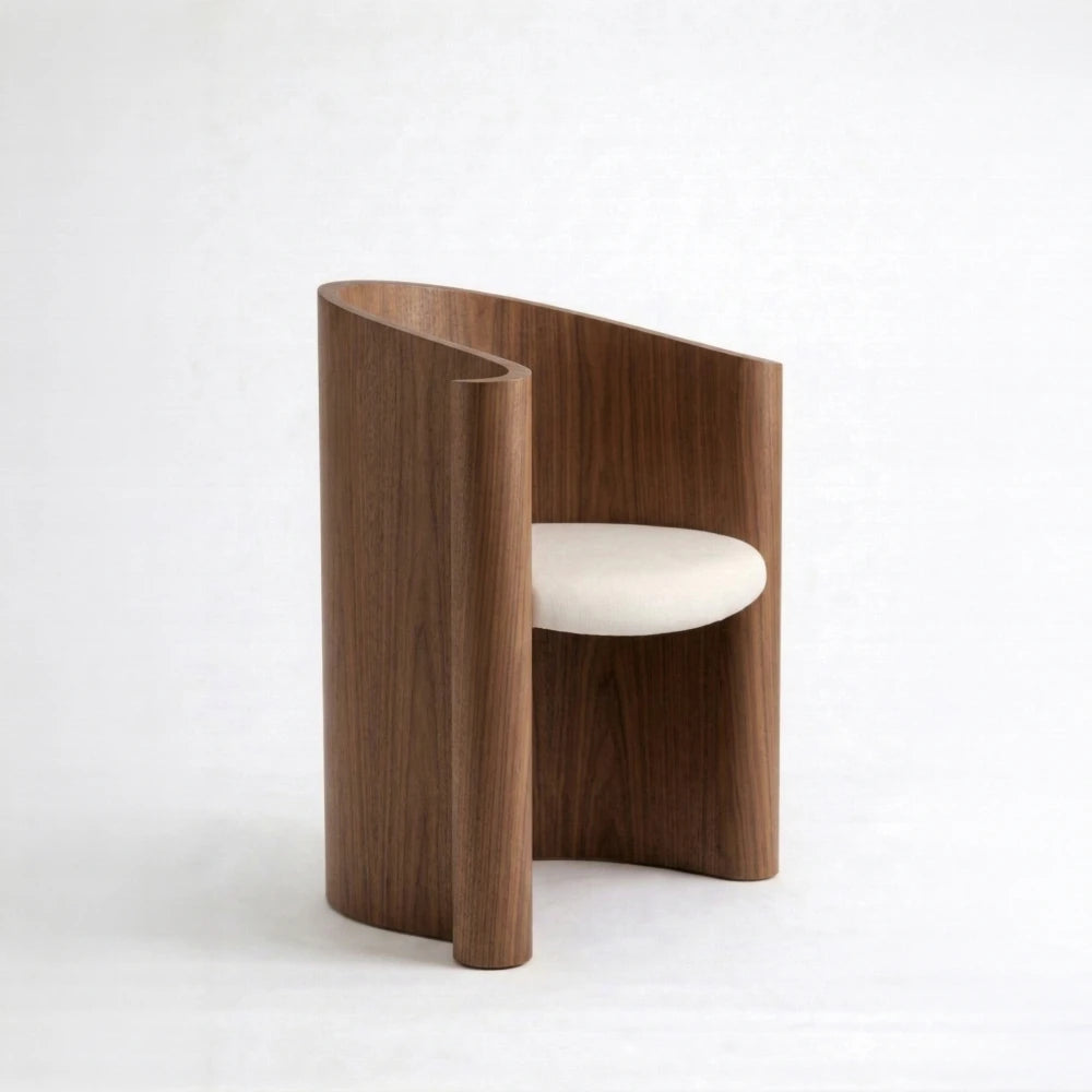 Walnut Volute Chair by Garnier Pingree, featuring a continuous curved shell, vertical wood grain and a cream upholstered seat.